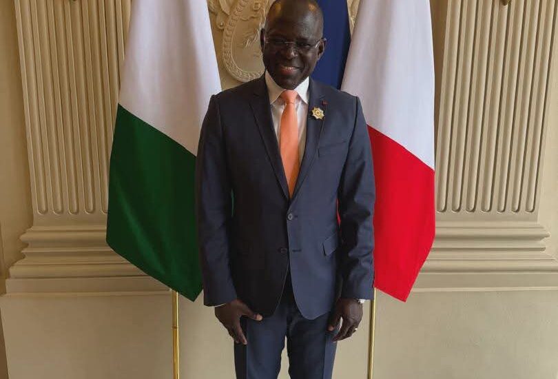 L'Honorable Penawelfa Karim Ouattara devant les drapeaux ivoirien et français